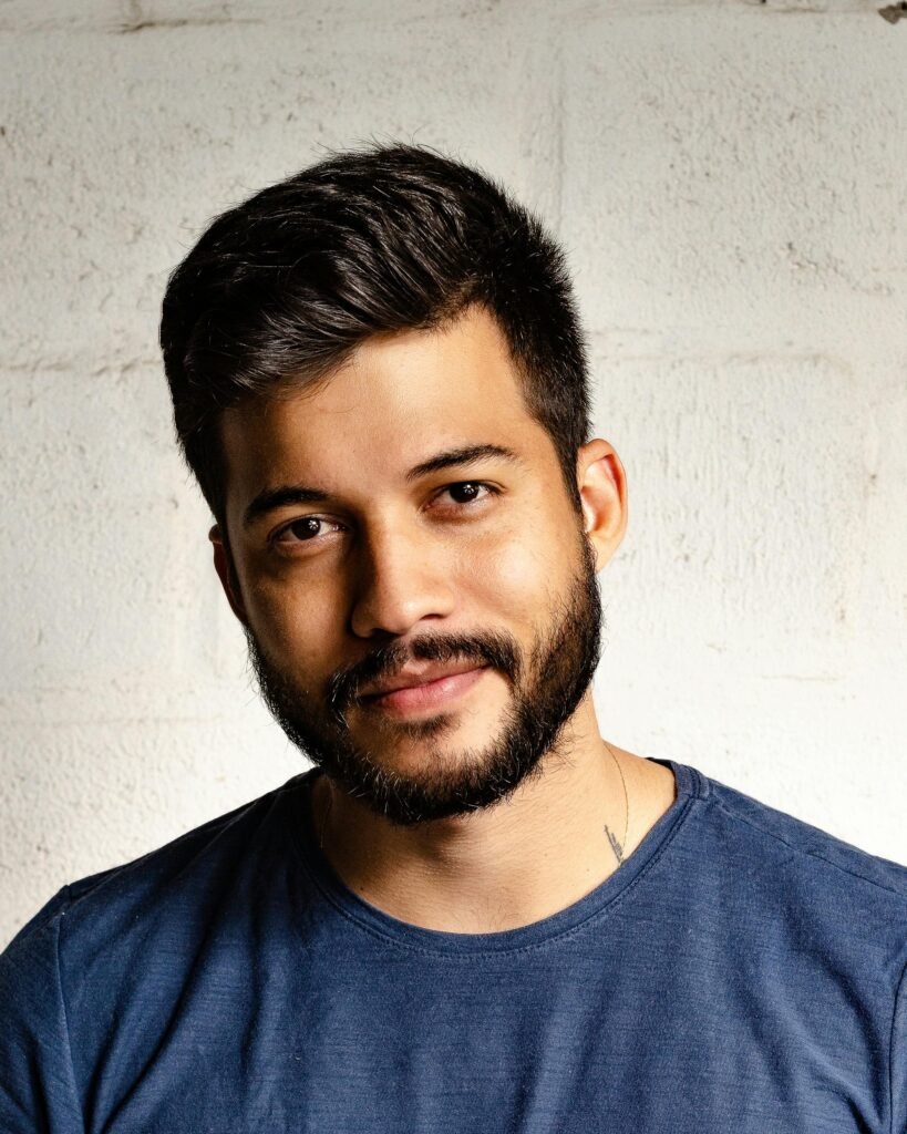 Close-up portrait of a handsome man with a beard in casual attire, smiling warmly.